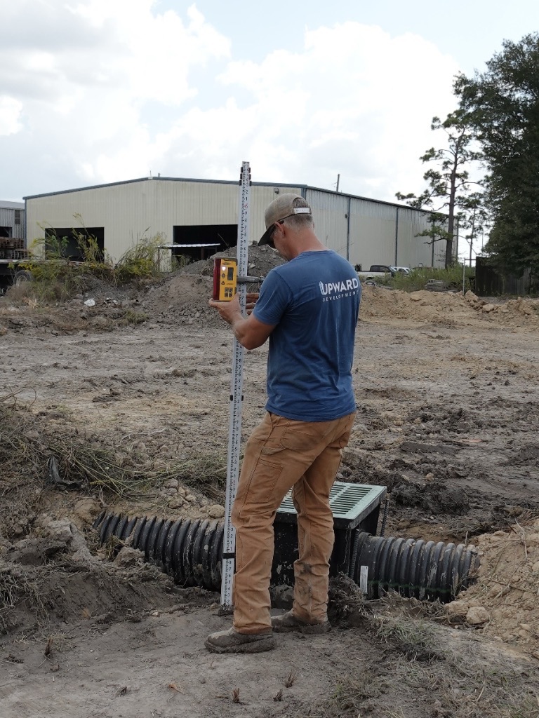 Crew member using laser grade equipment to check elevation on a job site