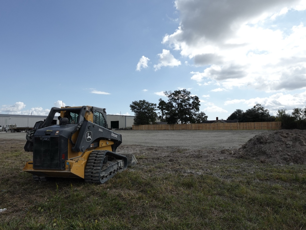 Skid steer with clearing attachment working a wooded lot